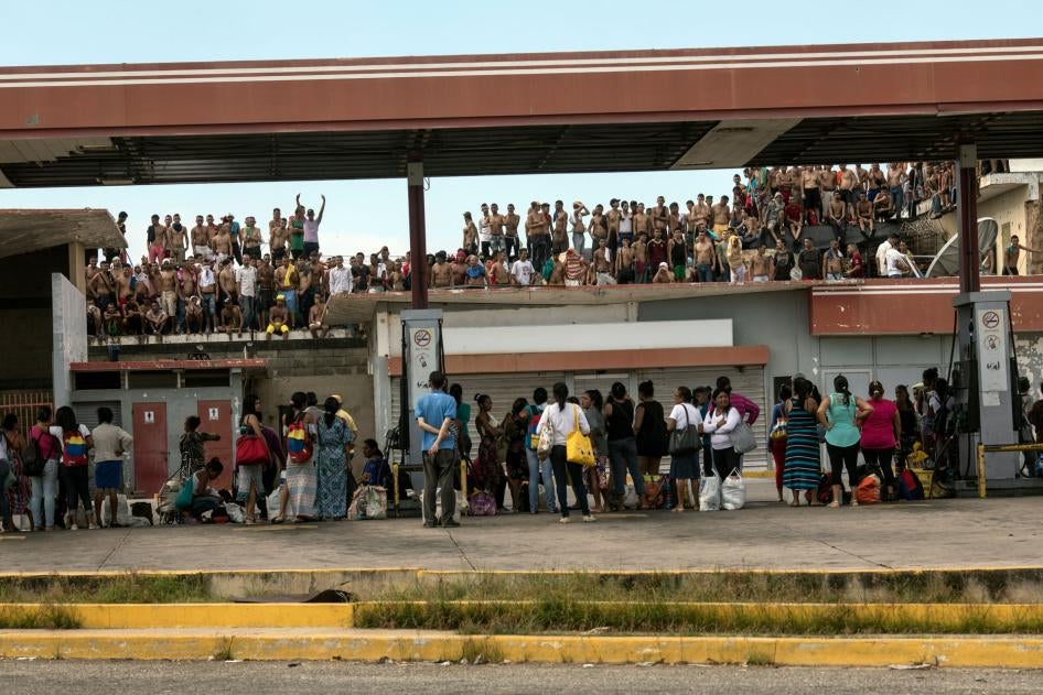 Reclusos en el techo del centro de detención Retén de Cabimas para reclamarle a los guardias que dejen a sus familiares, abajo, ingresar comida durante su día de visita, en Cabinas, Venezuela, 17 de noviembre de 2019. 