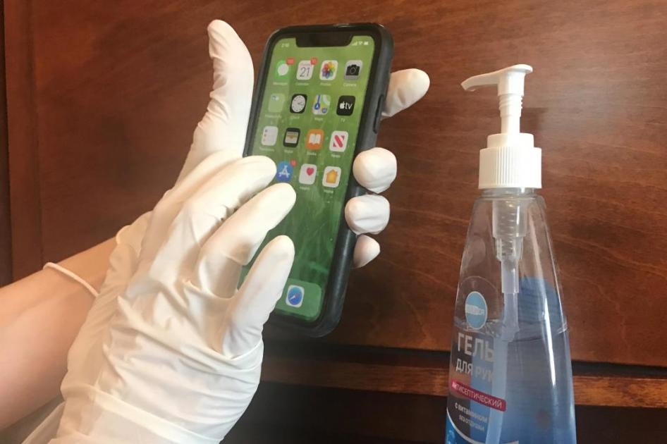 A woman in medical gloves holding an iPhone.