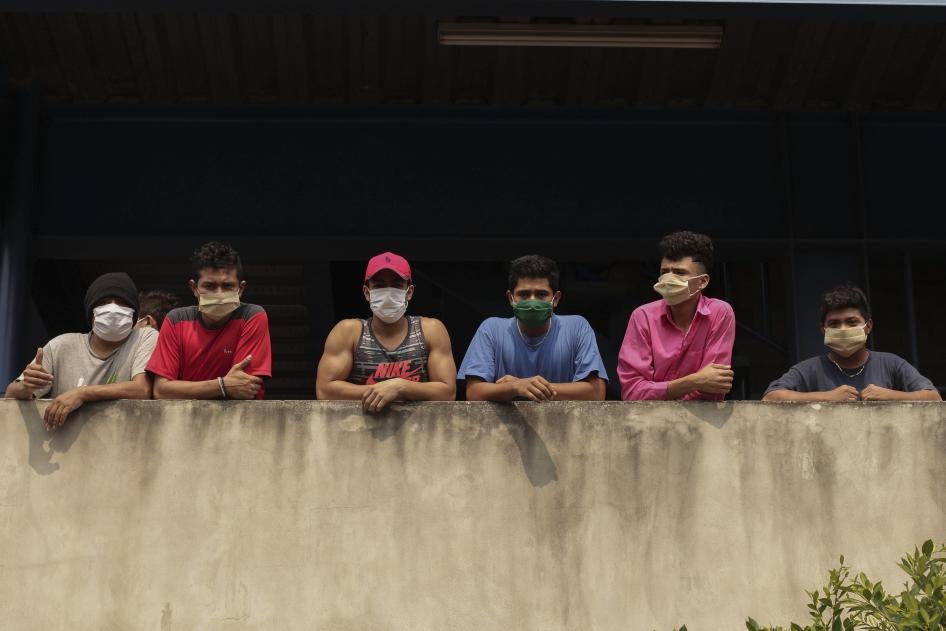 En esta imagen del 4 de mayo de 2020, un grupo de hombres con mascarilla miran desde el edificio donde están siendo confinados por violar la cuarentena decretada por el gobierno, como parte de las medidas para prevenir la propagación del Covid-19, en San Salvador, El Salvador.