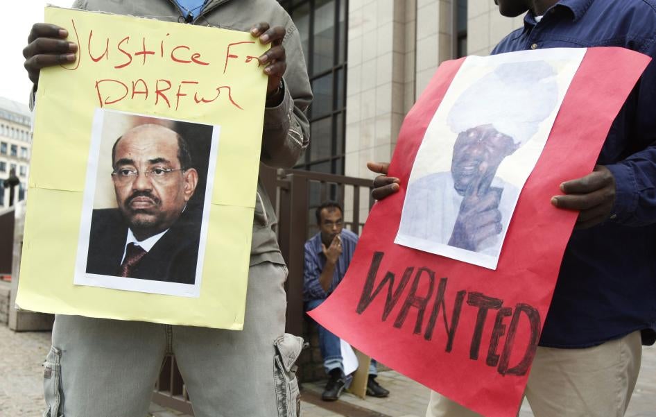 Des manifestants tenaient des affiches montrant Omar el-Béchir, qui était alors le président du Soudan, ainsi que le chef de milice Ali Kosheib, devant le siège du Conseil de l'Union européenne à Bruxelles, en juillet 2008. Les deux hommes étaient accusés par la CPI de crimes de guerre commis au Darfour.