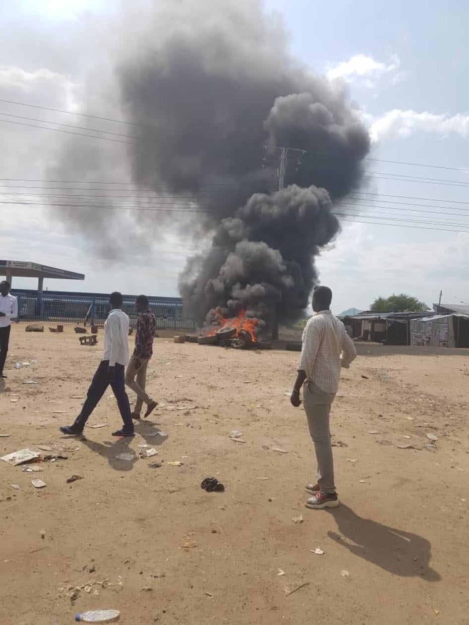 Civilians walk past burning tires during a protest in Shirkat, Juba, South Sudan on June 3, 2020. 