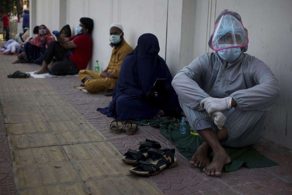 Patients sit on the ground as they wait in queue outside of a hospital for Covid-19 test in Dhaka, Bangladesh on May 16, 2020. 