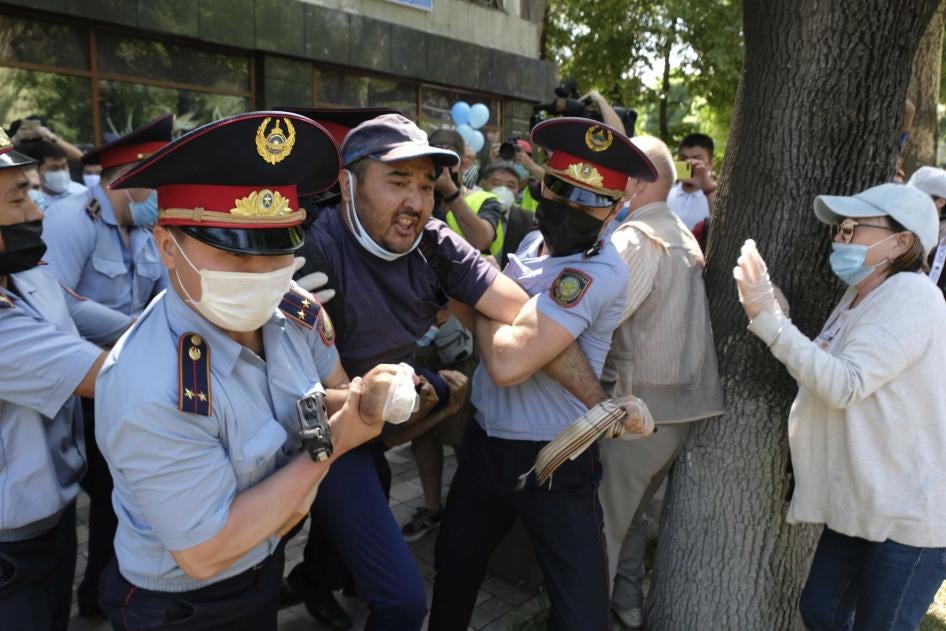 Полицейские в масках для защиты от коронавируса задерживают протестующего во время несанкционированного митинга в Алматы 6 июня 2020 года.