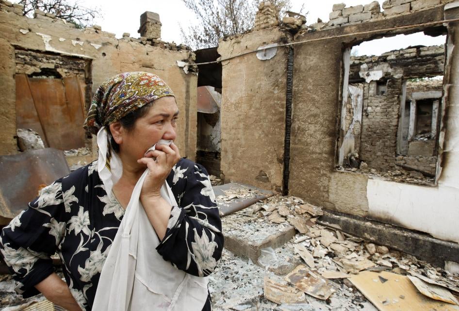 An ethnic Uzbek woman reacts as she stands at her house burnt down during clashes in the city of Osh, June 24, 2010.