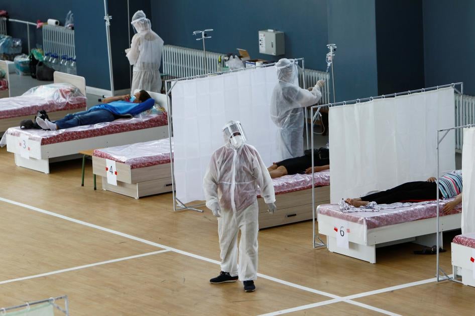Работники здравоохранения в средствах индивидуальной защиты (СИЗ) проводят лечение пациентов в дневном стационаре, предоставляющем услуги бесплатно в школьном спортзале г. Бишкек, Кыргызстан, 16 июля 2020 года.
