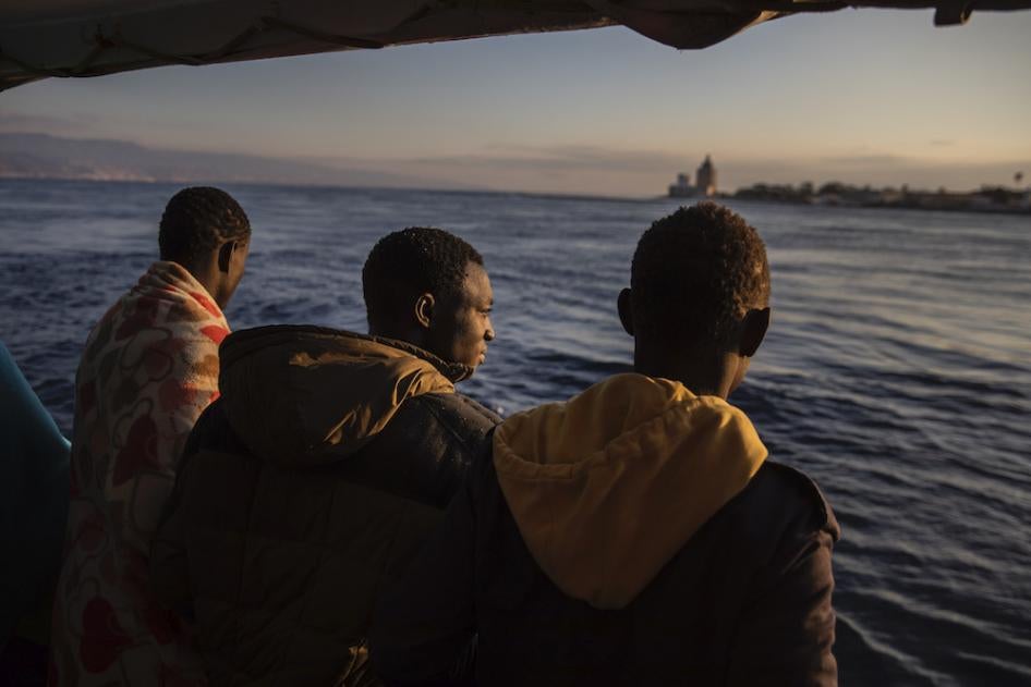 Men who were rescued off the Libyan coast in January, 2020 watch the city of Messina, Sicily from the deck of the Open Arms rescue vessel.
