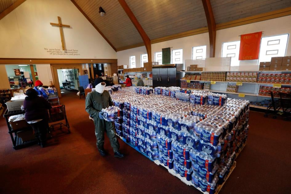 A man carries water for distribution at the Brightmoor Connection Food Pantry in Detroit, Michigan, March 23, 2020.