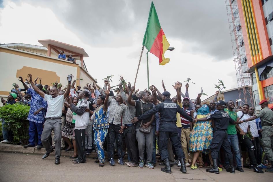 Des centaines de partisans lèvent les bras et agitent le drapeau national en attendant de saluer l’opposant camerounais Maurice Kamto, à Yaoundé le 5 octobre 2019, jour de sa sortie de prison.