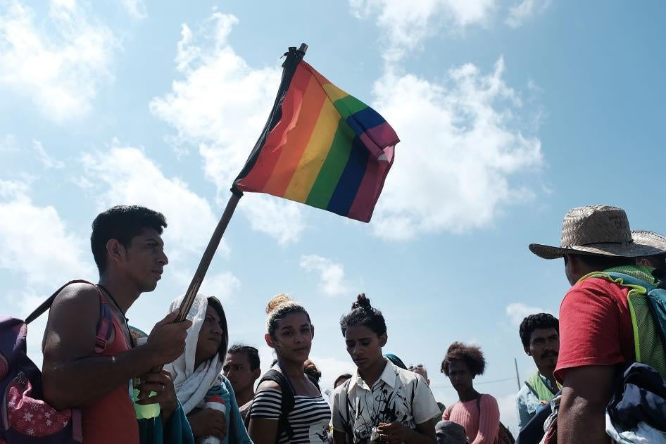 A group of men and women march walk while holding rainbow pride flags