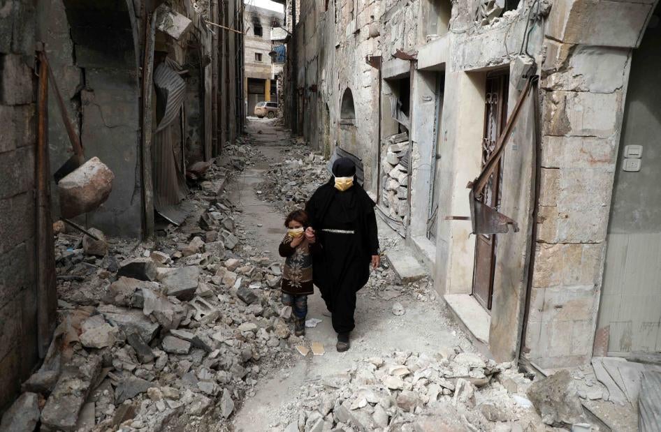 Une femme et sa fille, portant des masques faciaux pour se protéger contre le coronavirus, marchaient parmi des décombres dans une ruelle de la ville d'Ariha (gouvernorat d'Idlib) dans le nord-ouest de la Syrie, le 5 avril 2020.