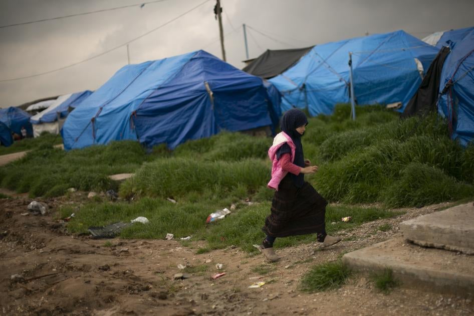A girl walks through a tented area at Roj camp.
