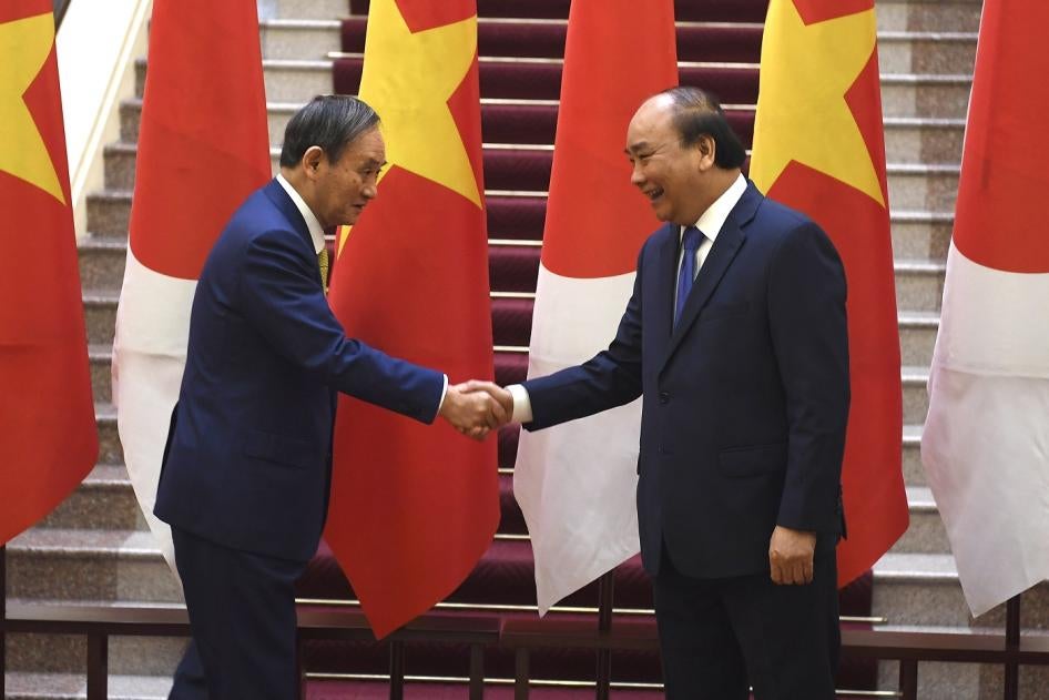 Japan's Prime Minister Yoshihide Suga, left, shakes hands with Vietnam's Prime Minister Nguyen Xuan Phuc after the exchange of documents at the Government Office in Hanoi on Monday, October 19, 2020. 