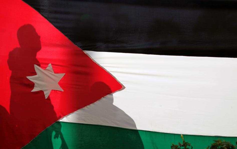 Silhouettes are cast on a Jordanian national flag in Amman, Jordan, November 30, 2016. 