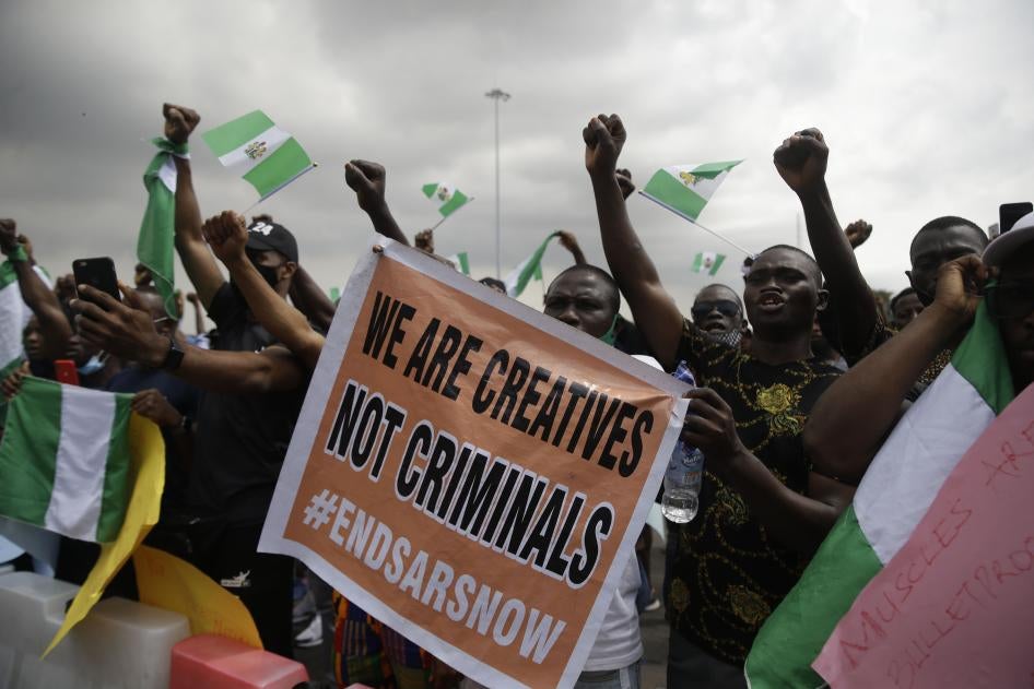 People hold banners and flags as they protest against police brutality in Lagos, Nigeria, Monday Oct. 19, 2020. 
