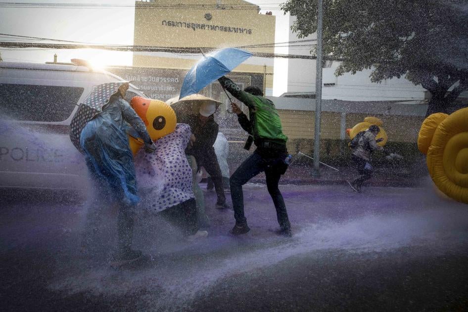 Democracy demonstrators take cover with inflatable ducks and umbrellas as police use water cannons during a protest rally near the parliament in Bangkok, November 17, 2020. © 2020 AP Photo/Wason Wanichakorn