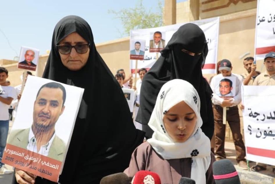 والدة توفيق المنصوري تحمل صورته، إلى جانب ابنته وزوجته في مظاهرة في 1 أكتوبر/تشرين الأول 2020. المنصوري هو أحد الصحفيين اليمنيين الأربعة مسجونين حاليا ويواجهون عقوبة الإعدام. © 2020 محمد العماد