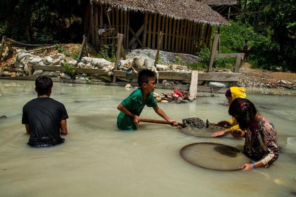 Four kids hold mining tools in a river