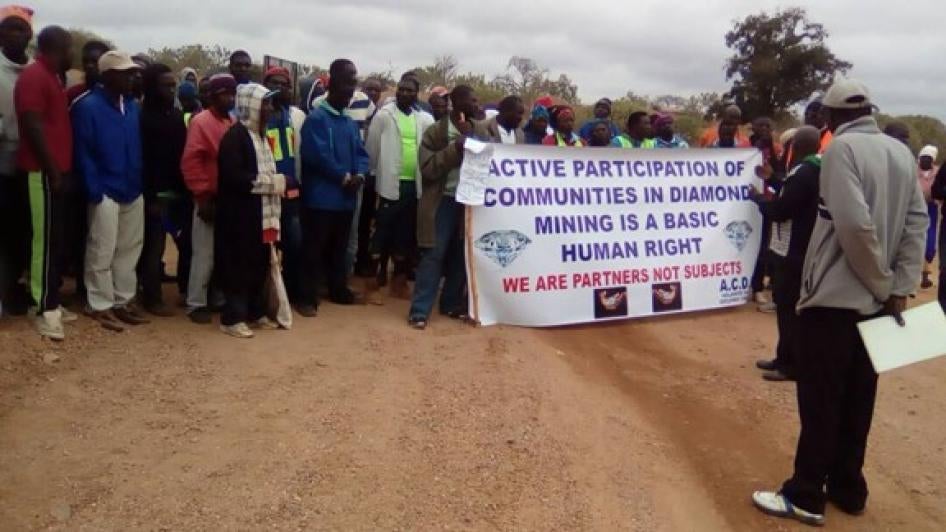 A group of protesters holds a sign that reads "Active Participation of Communities in Diamond Mining is a Basic Human Right."