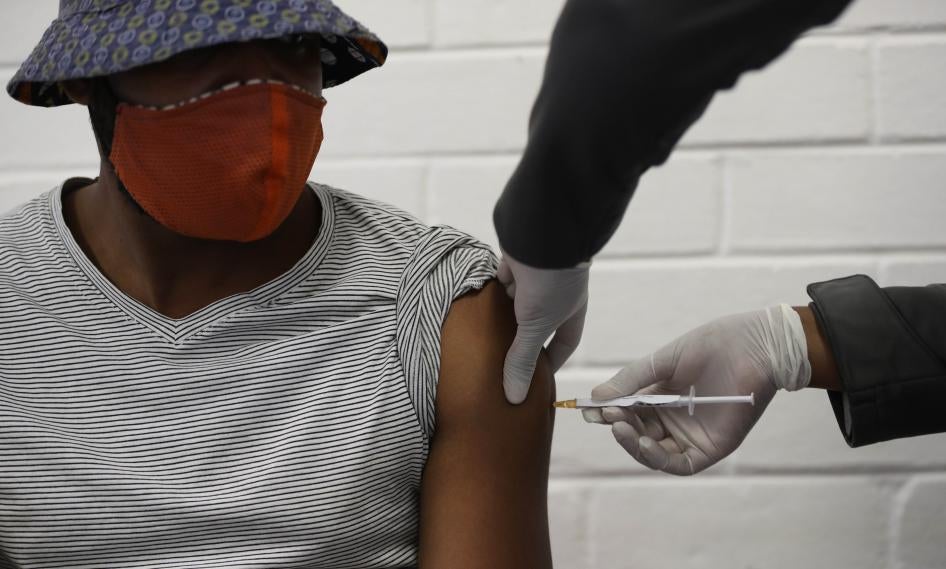A man wearing a mask receives a vaccination in the arm
