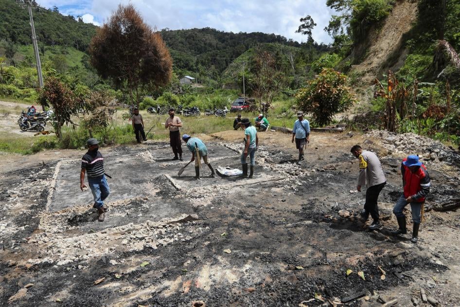 Warga desa dan aparat kepolisian membersihkan puing-puing di lokasi penyerangan yang dilakukan kelompok militan di Desa Lembantongoa, Kabupaten Sigi, Sulawesi Tengah, Indonesia, 30 November 3030.  