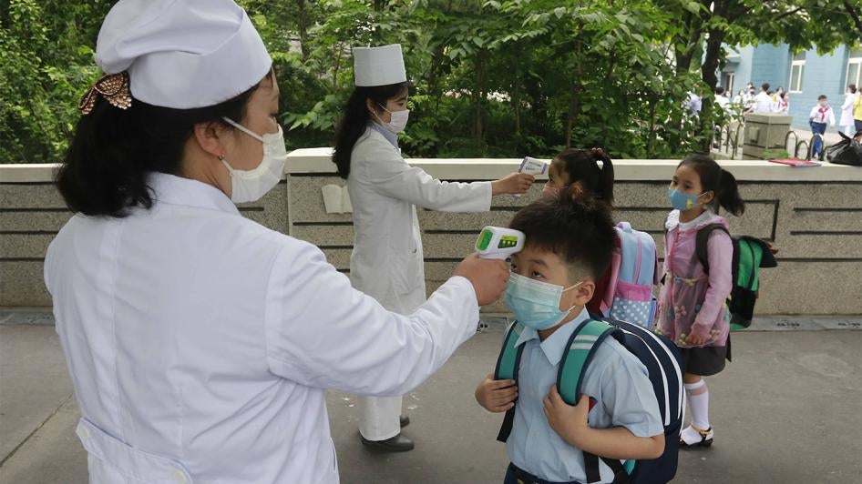 أطفال في "ابتدائية كيم سونغ جو" يصطفّون ليتم قياس حرارتهم قبل دخول المدرسة في بيونغيانغ، كوريا الشمالية. 