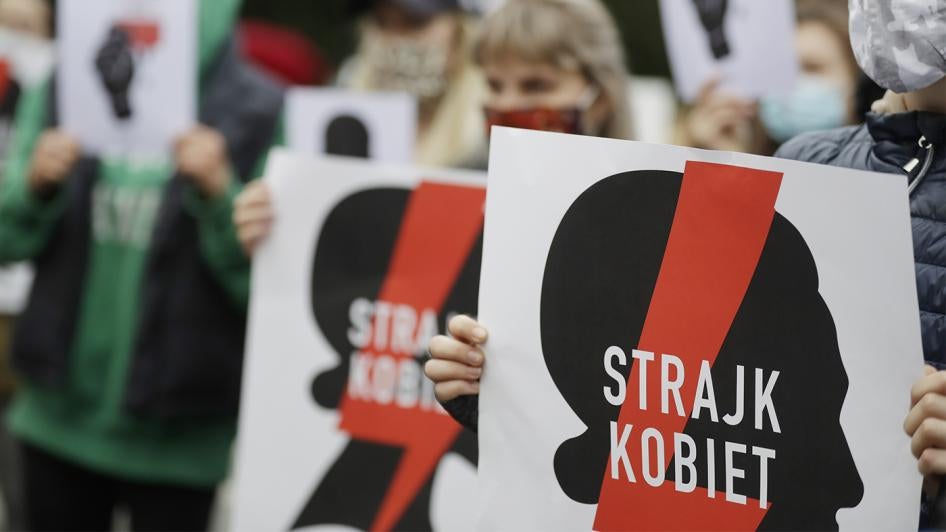 Women's rights activists, holding posters of the Women's Strike action, protest further tightening of Poland's restrictive abortion law in front of the parliament building in Warsaw, Poland, on Tuesday, October 27, 2020. 