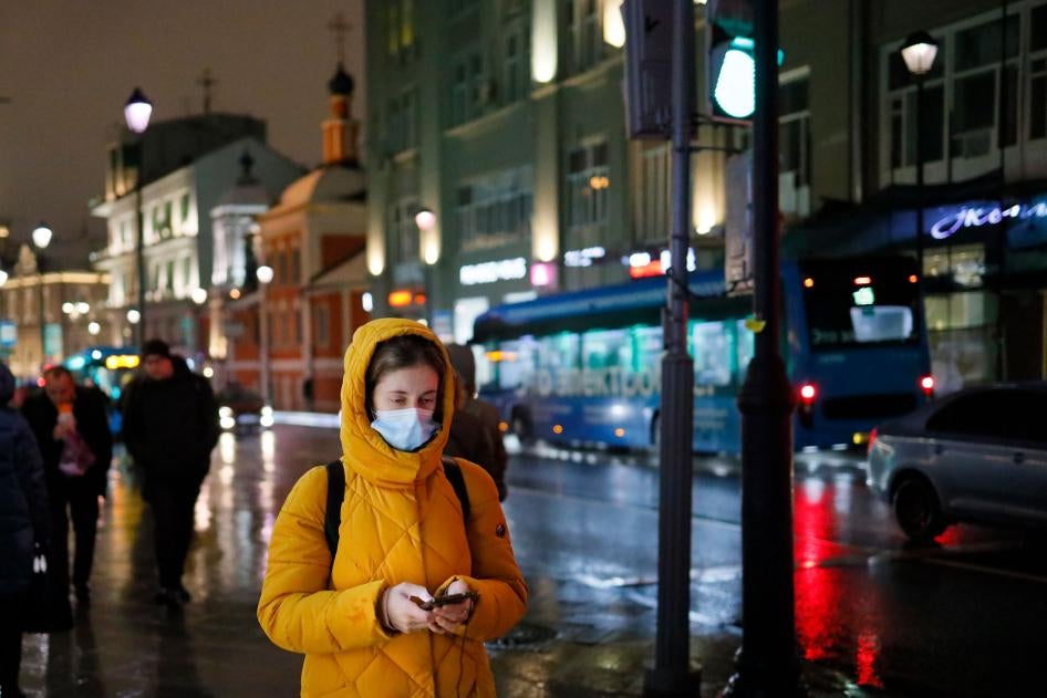 A woman wearing a face mask looks at her smartphone as she walks through a street in Moscow, Russia, November 23, 2020. 