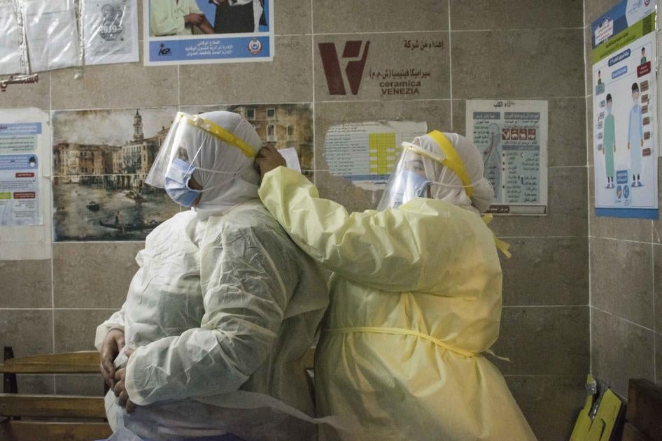 ممرضة تساعد زمليتها على ارتداء معدات الوقاية الشخصية في "مستشفى 6 أكتوبر المركزي"، وهو مستشفى عزل للمرضى المصابين بفيروس كورونا في الجيزة، القاهرة، يوليو/تموز 2020.