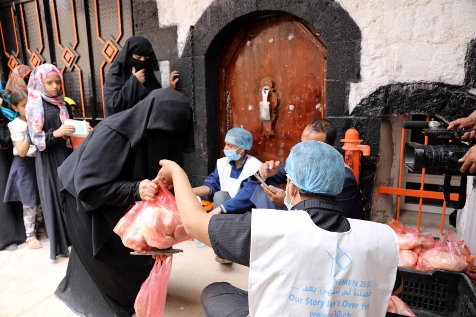An aid worker gives a food ration to a woman in Sanaa, Yemen, July 19, 2020