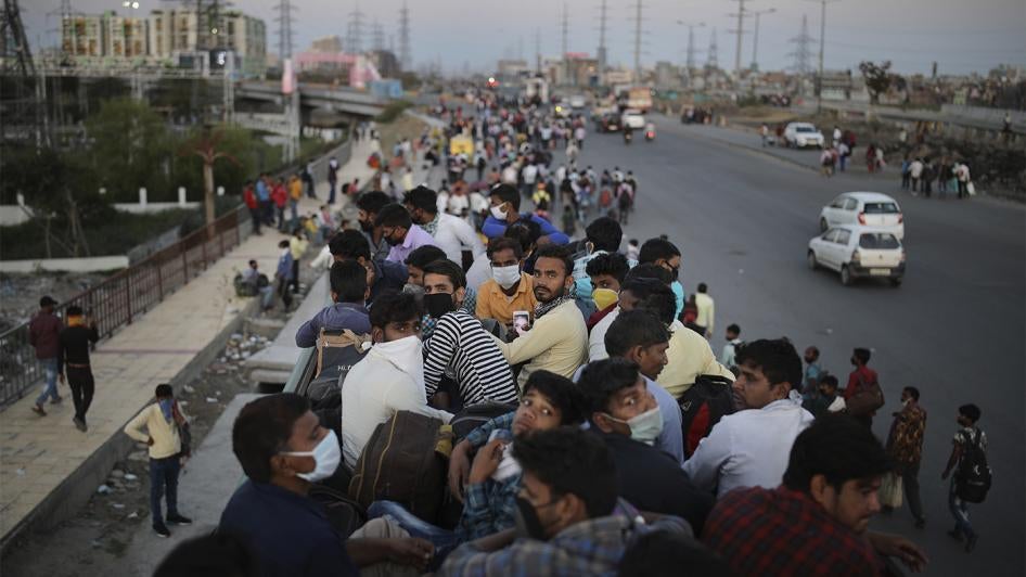 Indian migrant workers sit atop a bus as others walk along an expressway to return to their home villages during a nationwide Covid-19 lockdown, New Delhi, India, March 28, 2020.