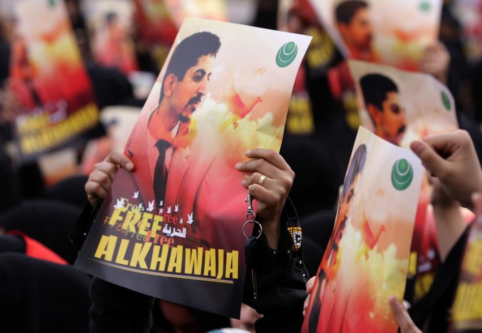 Bahraini anti-government protesters raise signs with images of jailed human rights activist Abdulhadi al-Khawaja Friday, April 6, 2012, in Jidhafs, Bahrain.