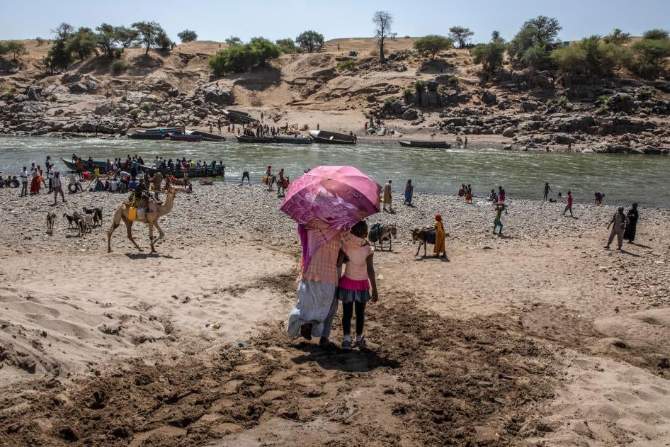 Refugees who fled the conflict in Ethiopia's Tigray region, which involved Eritrean as well as Ethiopian forces, arrive on the banks of the Tekeze River on the Sudan-Ethiopia border, November 20, 2020.