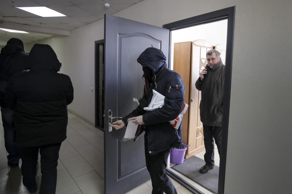 Police in Minsk carry documents and computers out of the office of the Belarusian Association of Journalists on February 16, 2021, as Andrei Bastunets, the head of the organization, looks on.