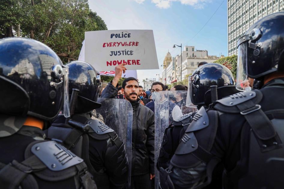 متظاهر يرفع لافتة كتب عليها "شرطة في كل مكان، لا عدالة في أي مكان" على إثر احتجاجات في مختلف أنحاء البلاد مطالبة بالعدالة الاجتماعية وإصلاحات حكومية في 23 جانفي/يناير 2021، شارع الحبيب بورقيبة، العاصمة تونس.