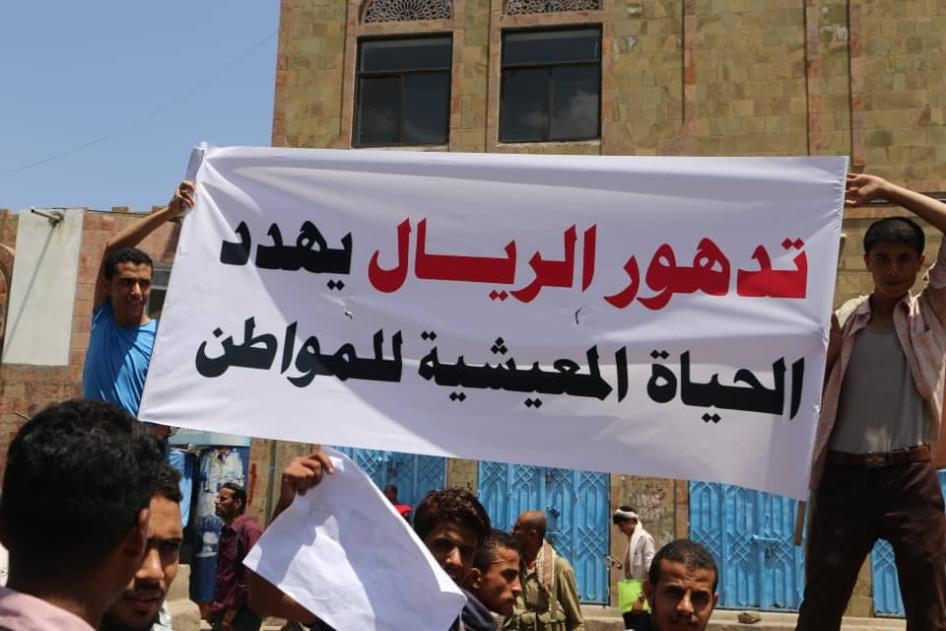 متظاهرون يحملون لافتة تقول: "تدهور الريال يهدد الحياة المعيشية للمواطن"، تعز، اليمن، ديسمبر/كانون الأول 2018. 