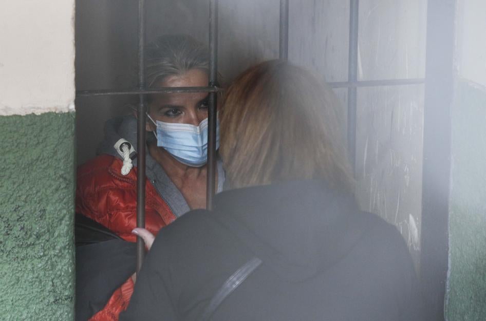 Standing behind bars, Bolivia's former interim President Jeanine Añez speaks to an unidentified woman at a police station jailhouse, in La Paz, Bolivia, on March 13, 2021.