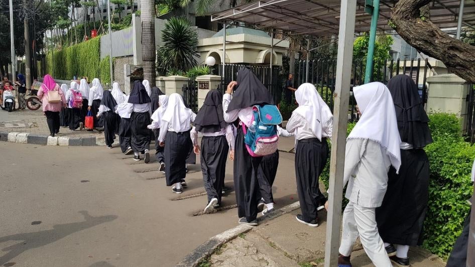 A group of schoolgirls walking on a sidewalk in jilbabs