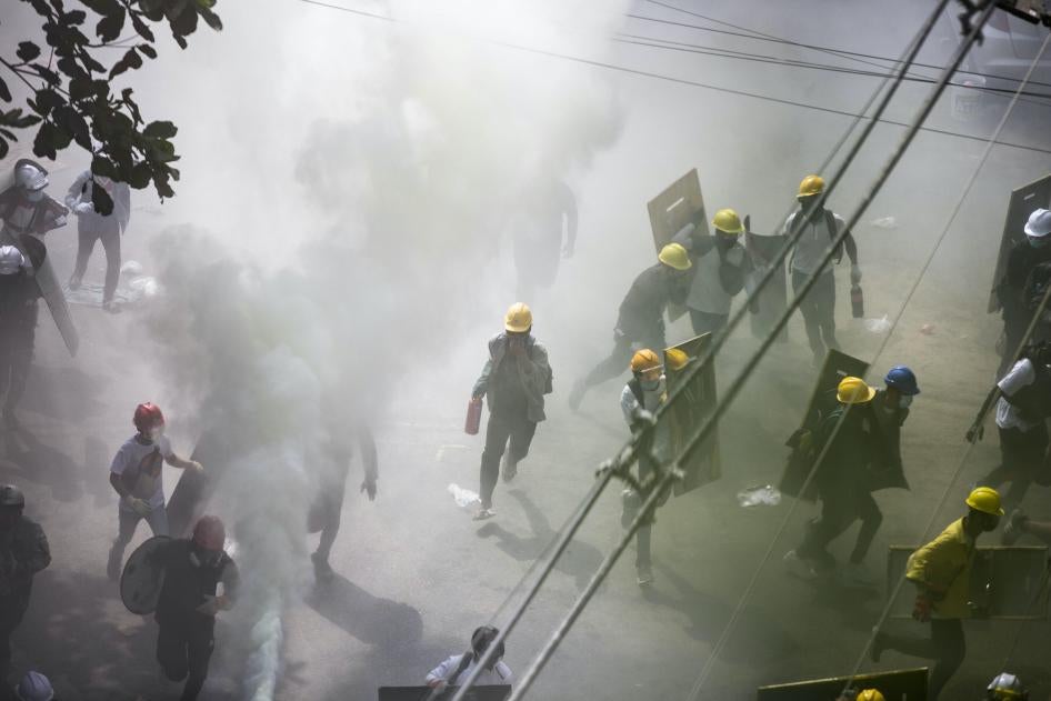 Des manifestants portant des casques de chantier, et dont certains tenaient des boucliers improvisés, couraient parmi des nuages de gaz lacrymogènes tirés par les forces de police anti-émeute à Yangon, au Myanmar, le 3 mars 2021.