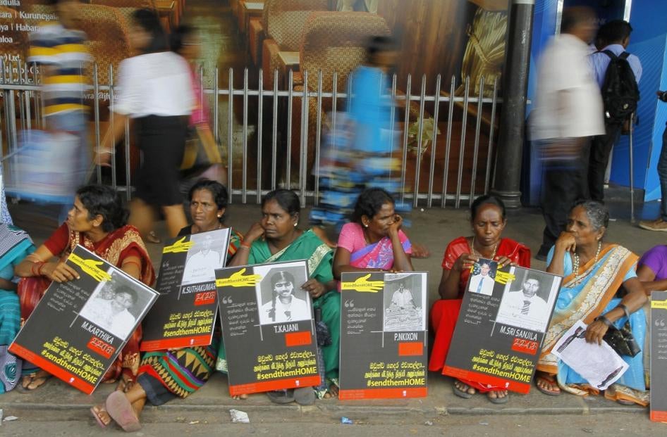 In this April 6, 2015, file photo, Sri Lankan ethnic Tamil women sit holding placards with portraits of their missing relatives as they protest out side a railway station in Colombo, Sri Lanka.