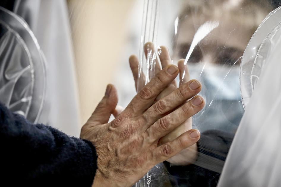 Relatives touch each other's hand through a plastic film screen and a glass to avoid contracting Covid-19 at the San Raffaele center in Rome, Italy, Dec. 22, 2020