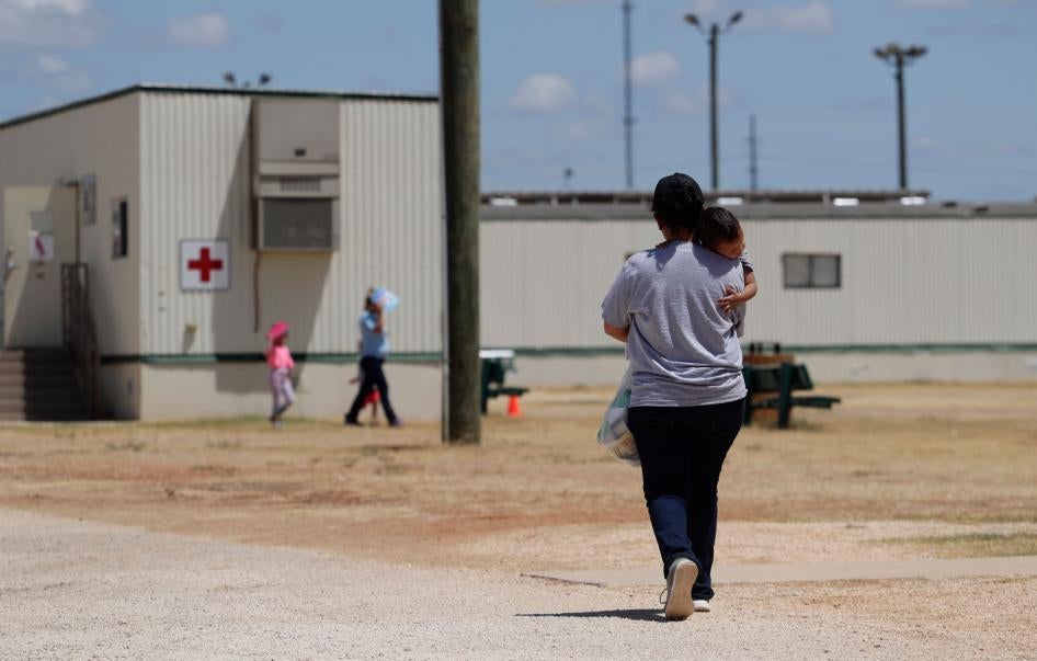 A woman walks carrying her child at the US Immigration and Customs Enforcement (ICE) South Texas Family Residential Center, in Dilley, Texas, August 23, 2019. 