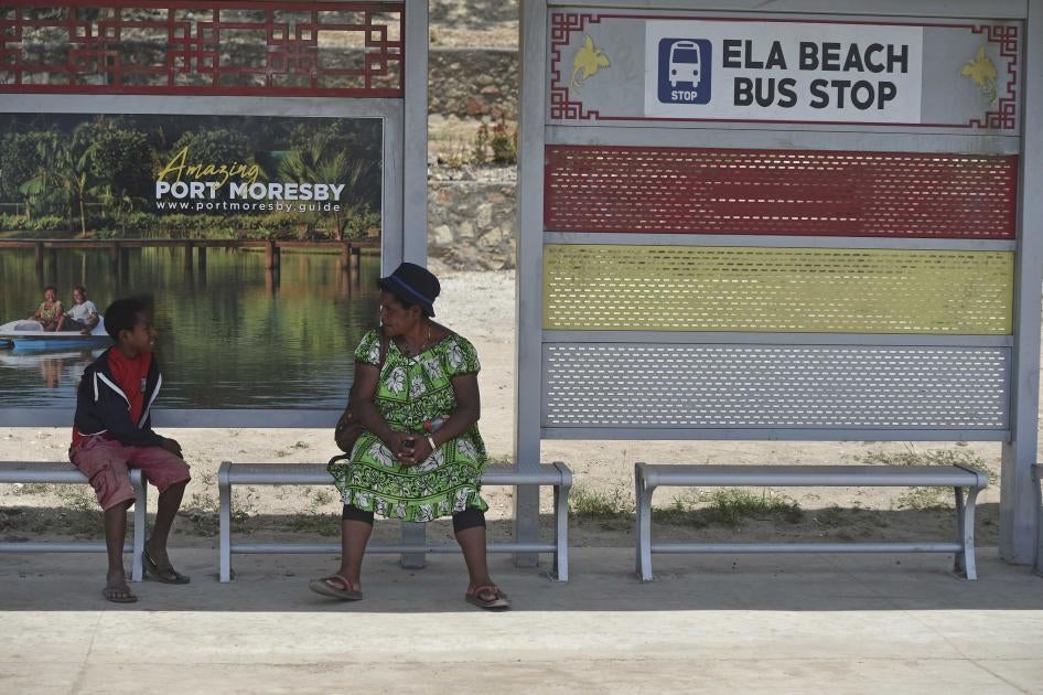 A boy and a woman at a bus stop in Port Moresby.