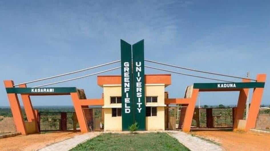Photo shows Greenfield University in Nigeria, in the daylight with a green sign reading the university's name.