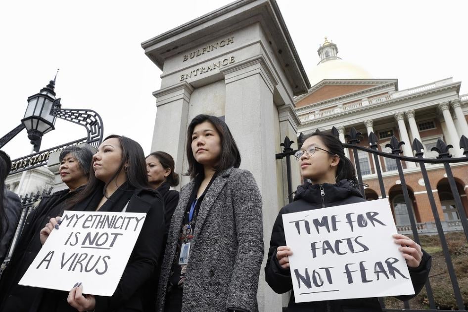 Asian American women stand together during a protest on the steps of the State House in Boston on March 12, 2020.
