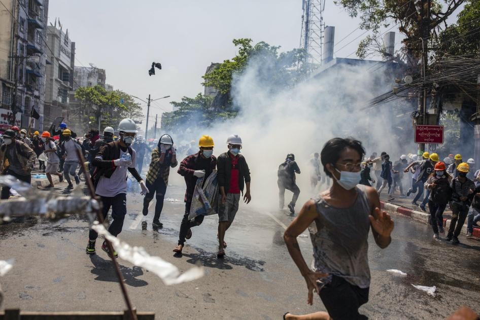 Des manifestants, dont un grand nombre portaient des casques jaunes et blancs, fuyaient sous des nuages de gaz lacrymogènes tirés par la police à Yangon, au Myanmar, le 1er mars 2021. Ces manifestants avaient tenté d’exprimer leur opposition au coup d'État militaire mené un mois auparavant, le 1er février 2021.