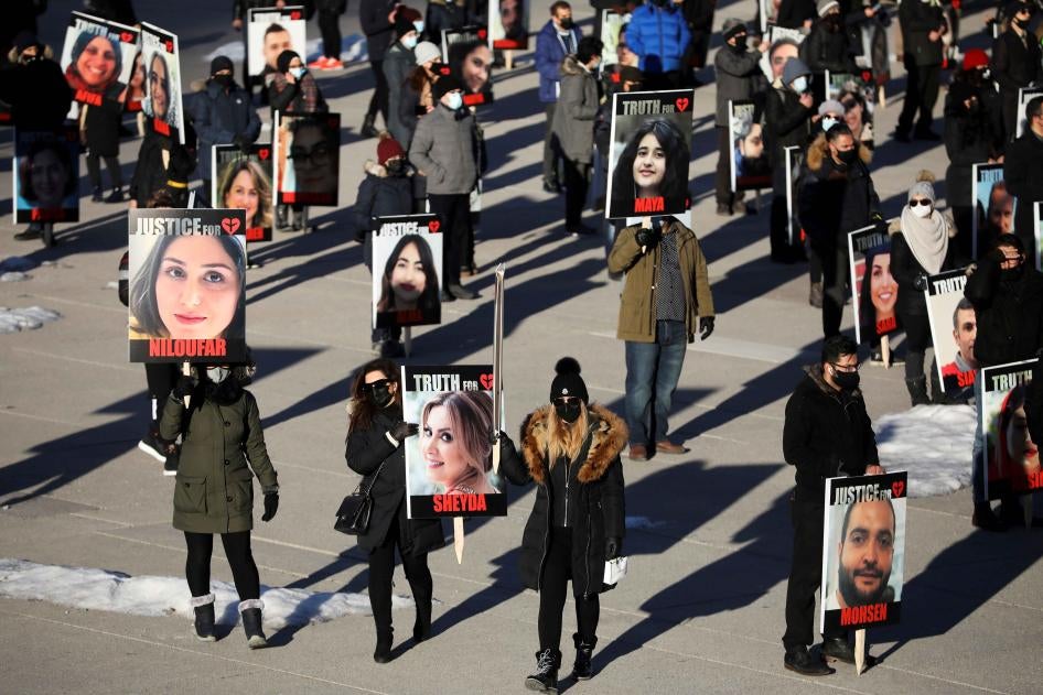 People hold placards with images of the victims of Ukraine International Airlines flight 752, which Iran's Revolutionary Guards shot down near Tehran, marking its first anniversary, in Toronto, Canada, January 8, 2021.