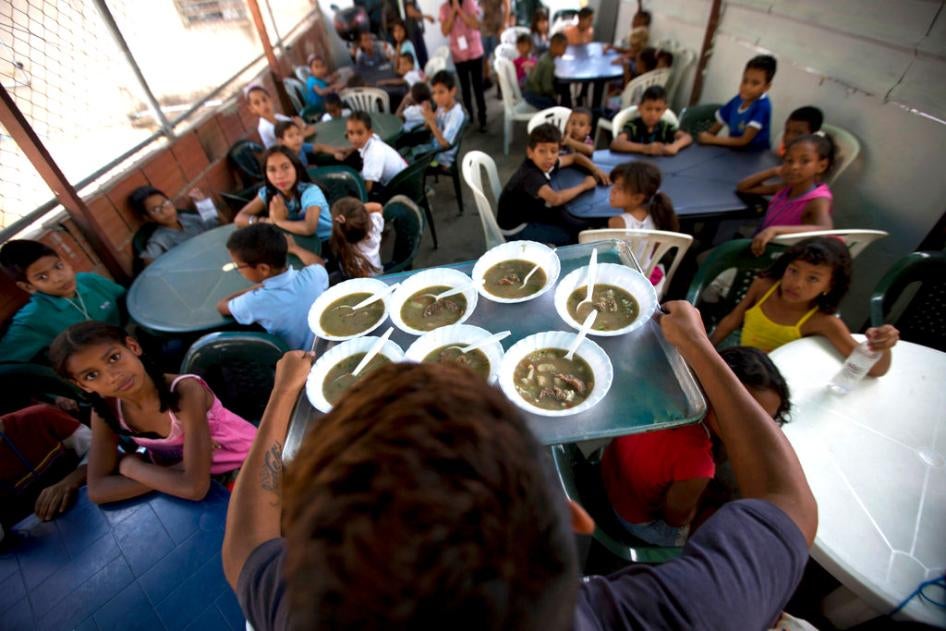 En esta foto del 12 de diciembre de 2017, niños y niñas observan cuando llega su comida en un comedor financiado por la oposición en Caracas, Venezuela.