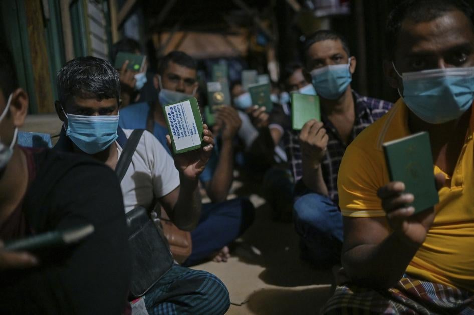 Migrant workers show their passport during a raid in Dengkil, outside Kuala Lumpur, Malaysia on June 21, 2021.
