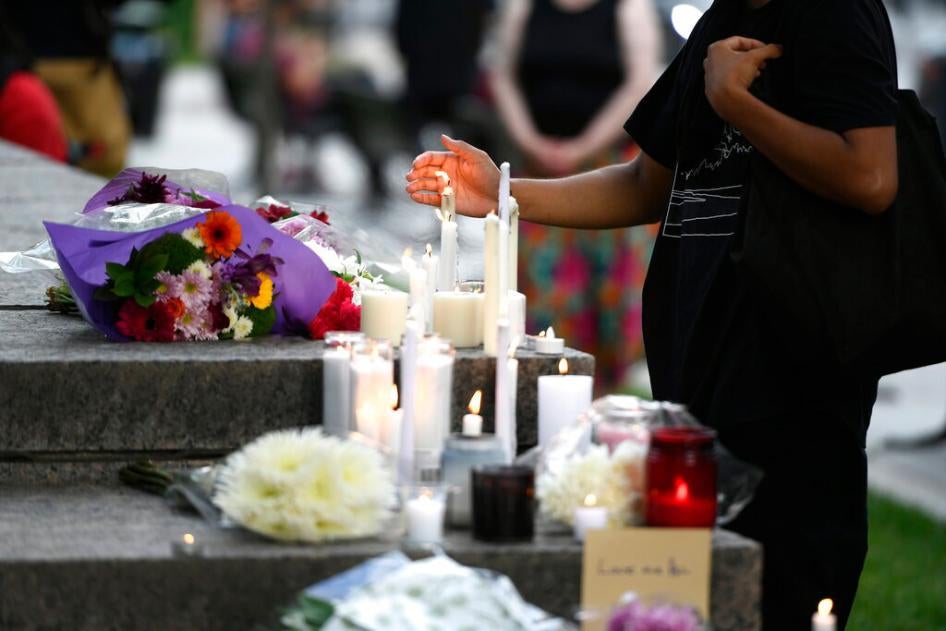 A mourner shields a candle from the wind after placing it at a memorial for the four family members who were killed in a vehicle attack in London, Ontario, in Ottawa, on Tuesday, June 8, 2021.