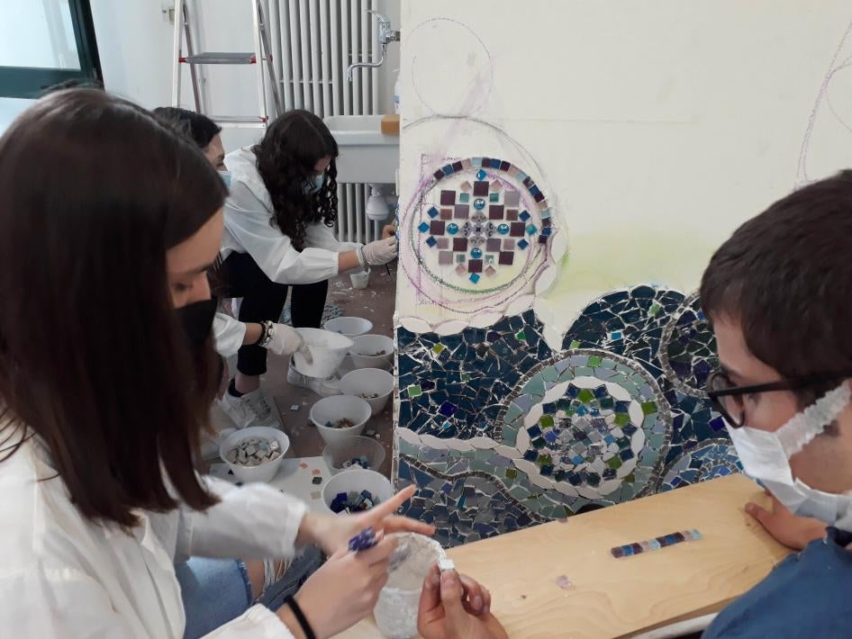 Students working on a mosaic on a wall.